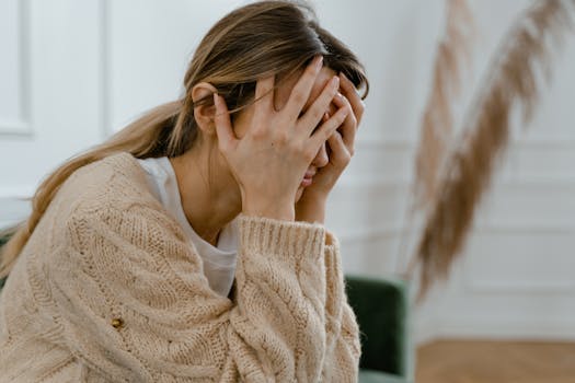 pexels photo 7699511 7699511 A woman sitting indoors covering her face in frustration, depicting stress and mental health challenges.